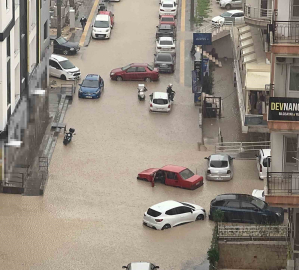 Yağmurda mahsur kalan motosikletli çareyi otomobilin üzerine çıkmakta buldu